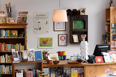 Ladentheke der Buchhandlung Murkelei mit Bücherregal links und einer hängenden Holzvitrine hinter der Theke